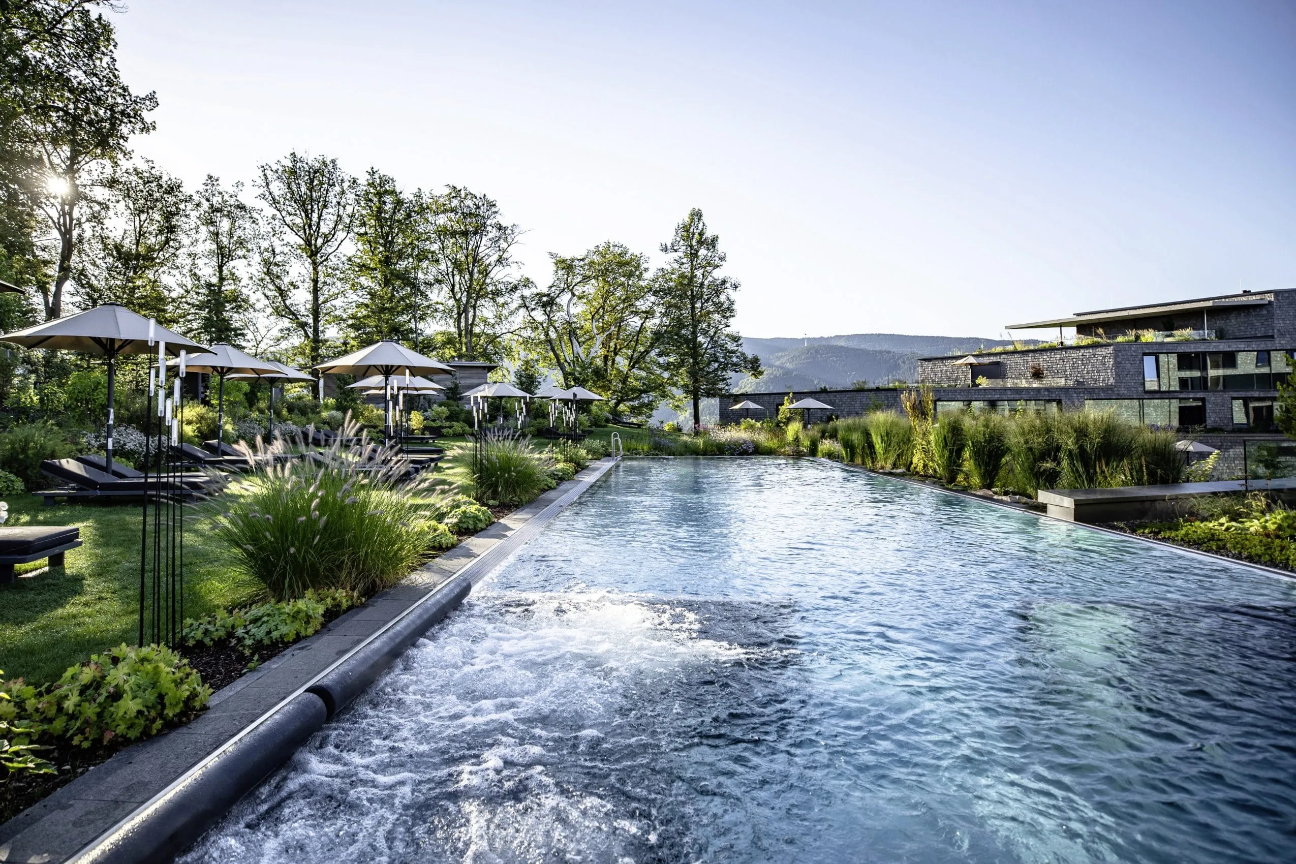 Outdoorpool im Luisenh&ouml;he Gesundheitsresort mit Liegest&uuml;hlen, Sonnenschirmen und Schwarzwald-Panorama