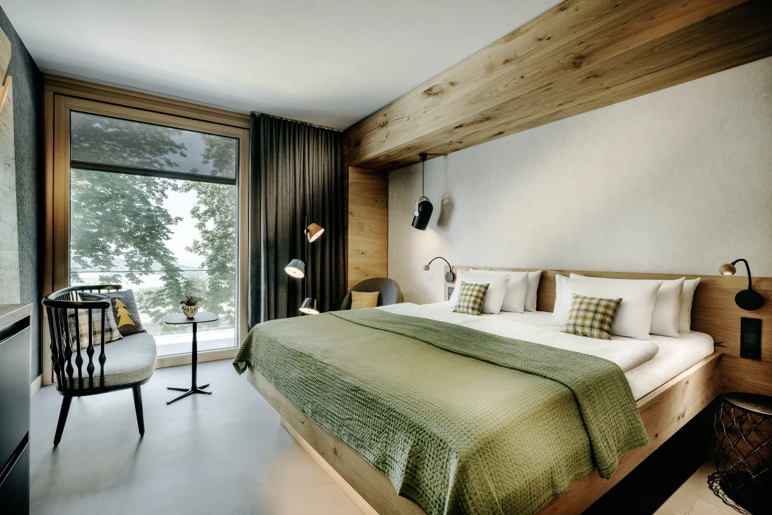 Doppelzimmer im Wellnesshotel im Schwarzwald mit Holzelementen, gr&uuml;ner Tagesdecke und Waldblick