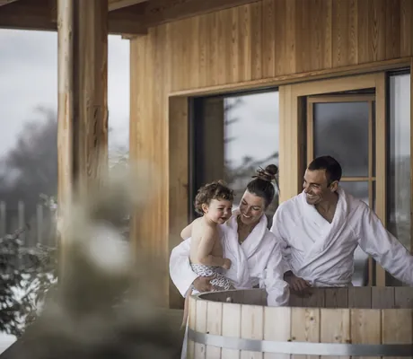 Familie mit Kleinkind in weißen Bademänteln steht am Hot Tub in Kesslers Mountain Lodge