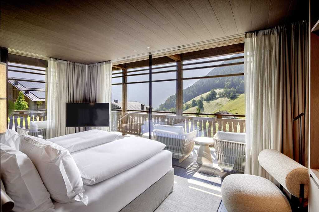 Zimmer in den Amonti Chalets mit Blick vom Doppelbett aus auf die Wiesen der Region