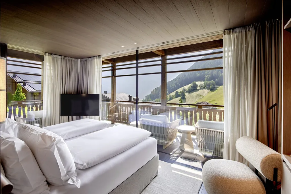 Zimmer in den Amonti Chalets mit Blick vom Doppelbett aus auf die Wiesen der Region