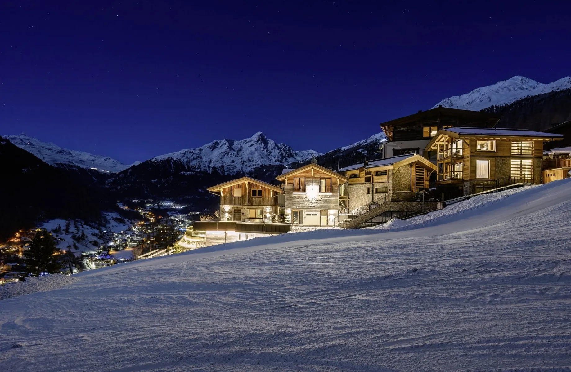 beleuchtete Fassade des The Peak Sölden mit Spa-House bei Nacht im Schnee