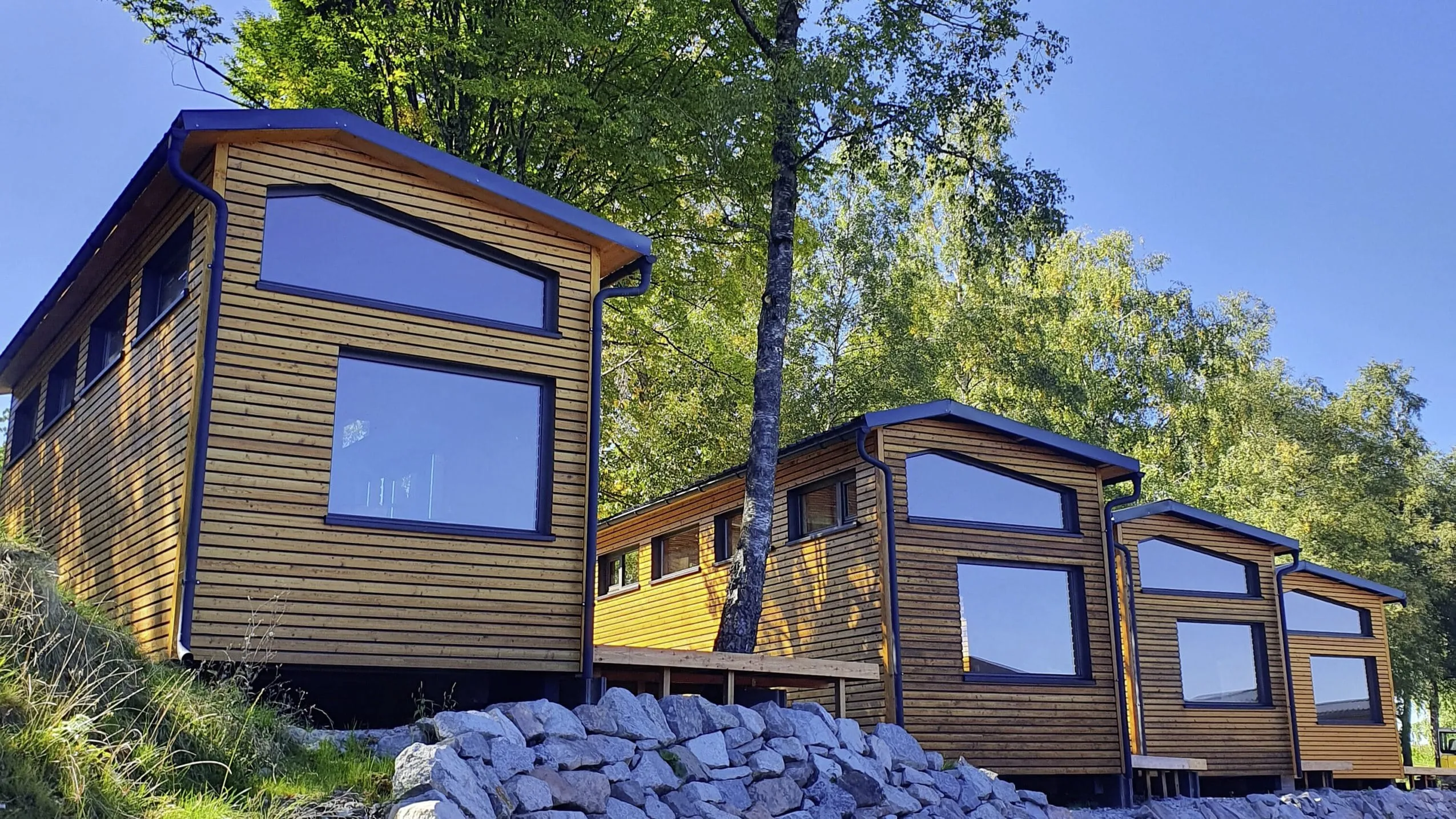Au&szlig;enansicht der SEINZ Wisdom Resort Tiny Houses mit Holzfassade am Waldrand