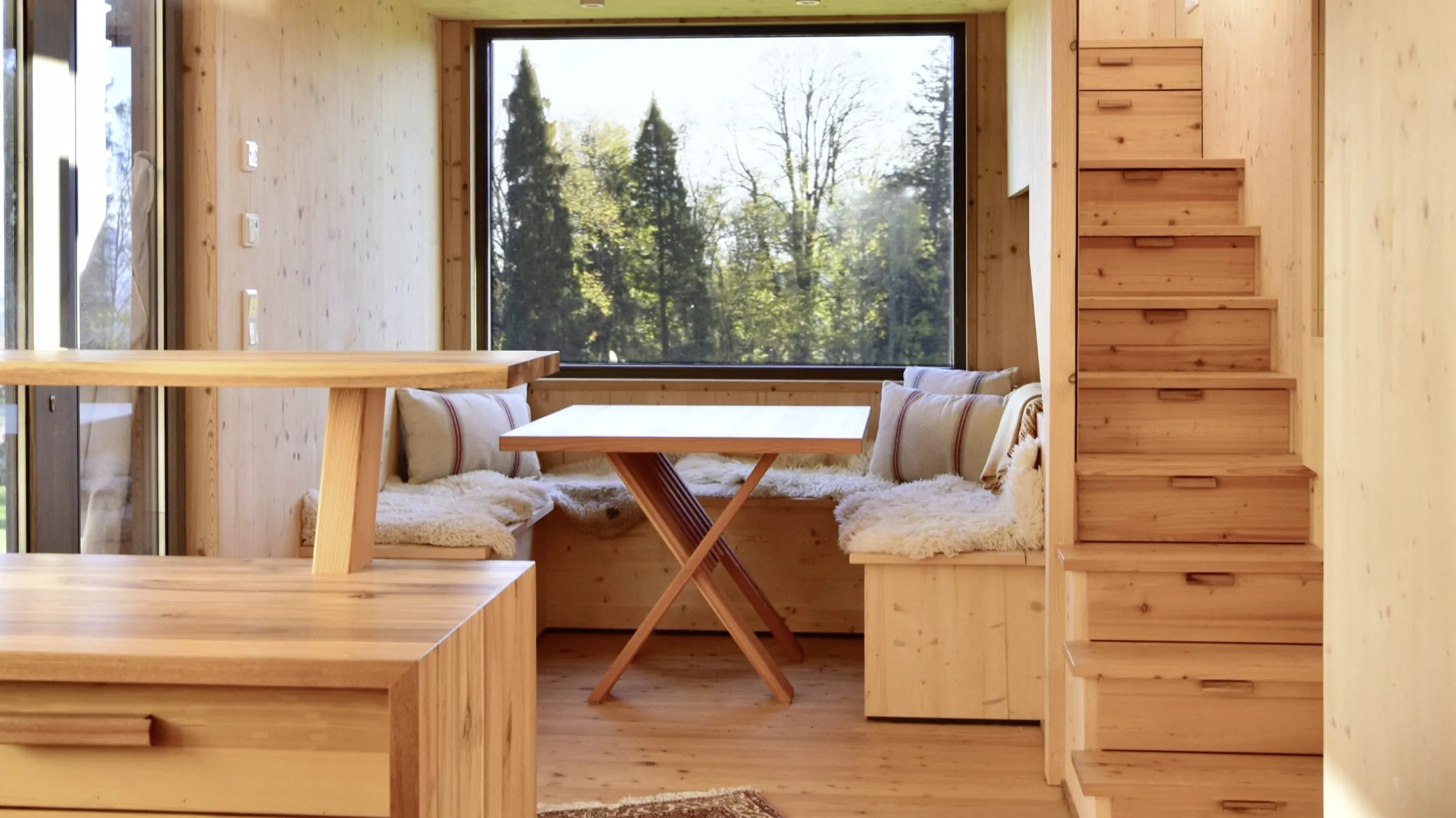 Gem&uuml;tlicher Wohnraum im Tiny House des SEINZ Wisdom Resorts mit Holzinterieur, Sitzecke und Panoramafenster