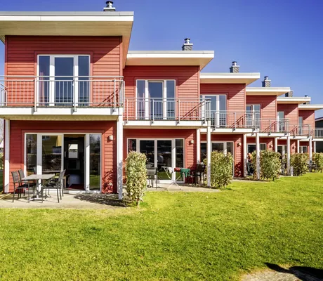 rote Ferienhäuser mit Terrasse hintereinander in der Reihe im Damp Resort Ostsee