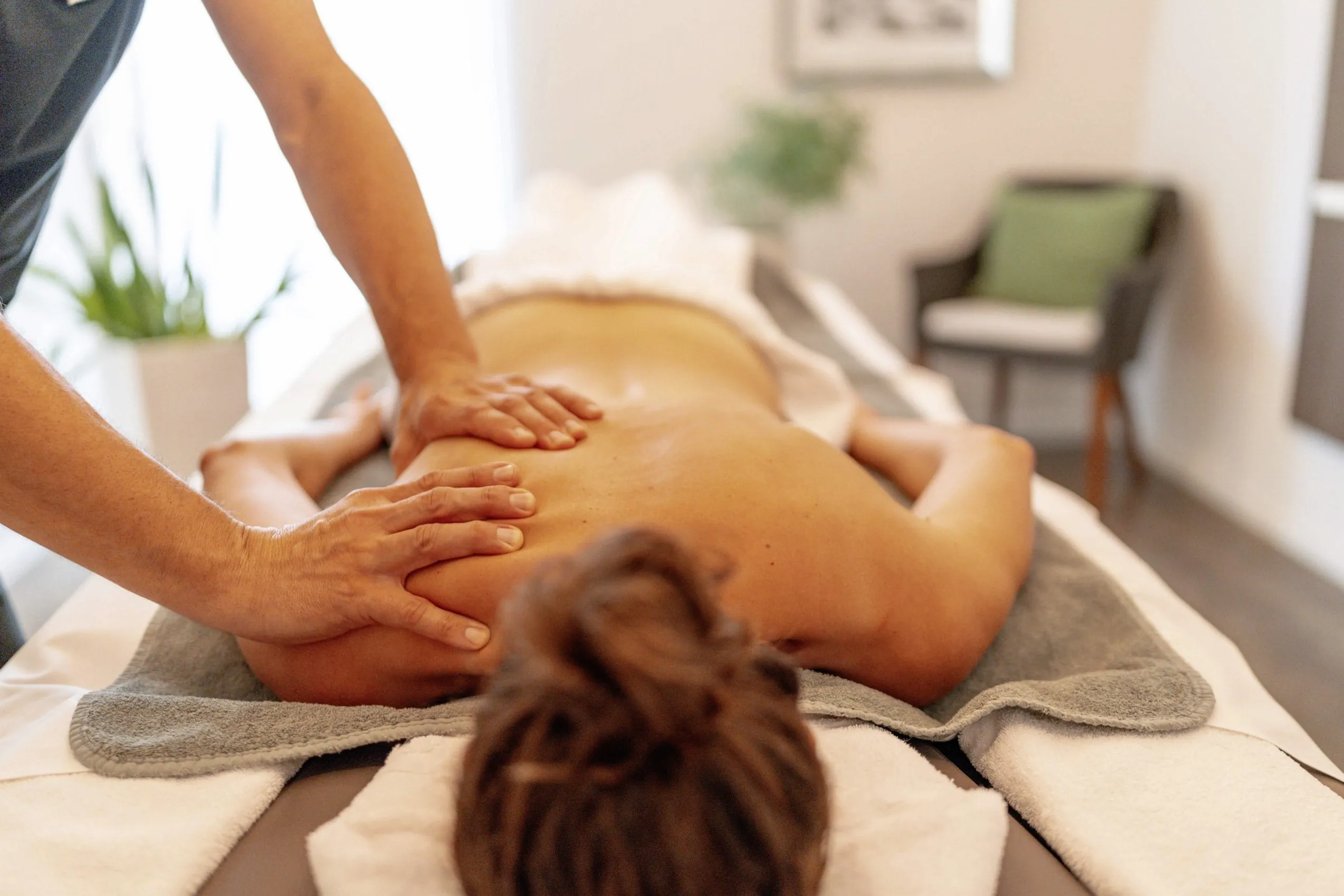 Frau bekommt eine R&uuml;ckenmassage in einem stilvoll eingerichteten Raum im Hotel Franks