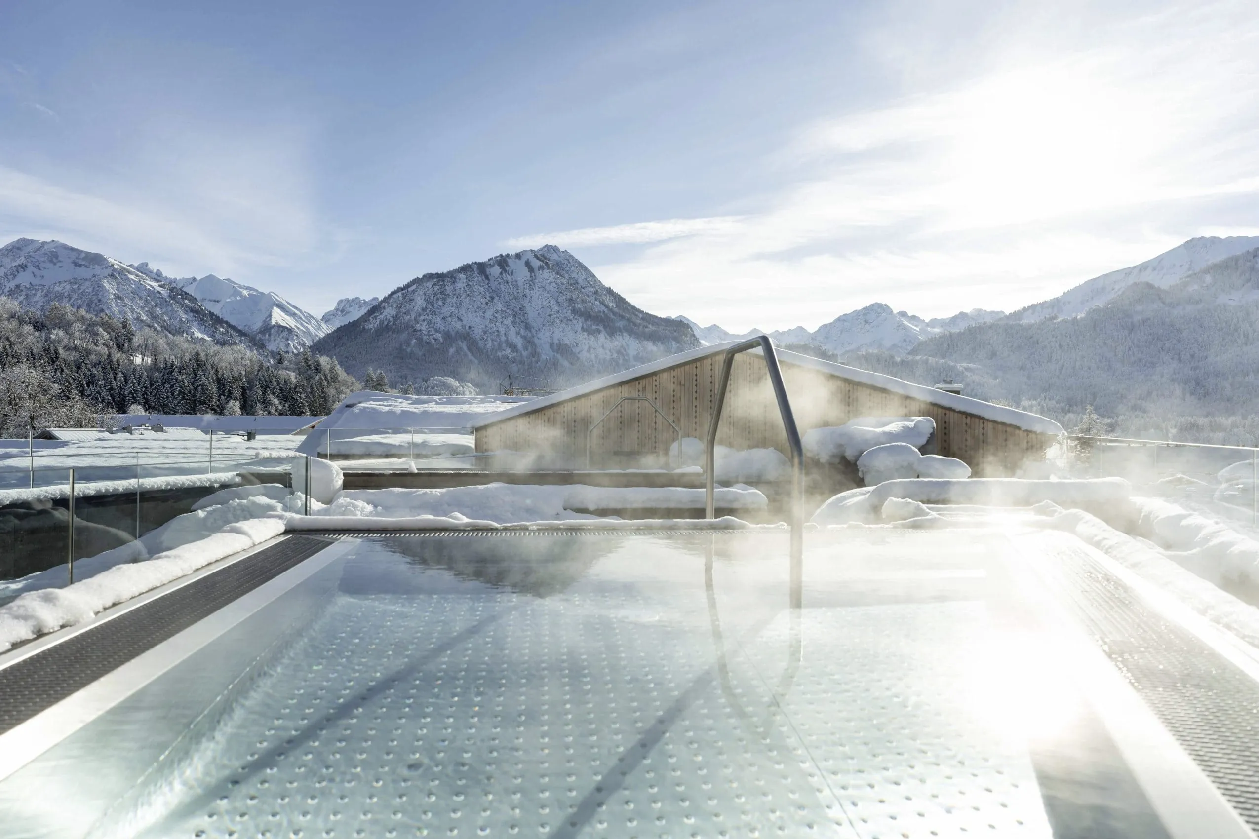 Beheizter Rooftop-Pool des Hotels Franks im Winter mit Alpenpanorama und Dampf &uuml;ber dem Wasser