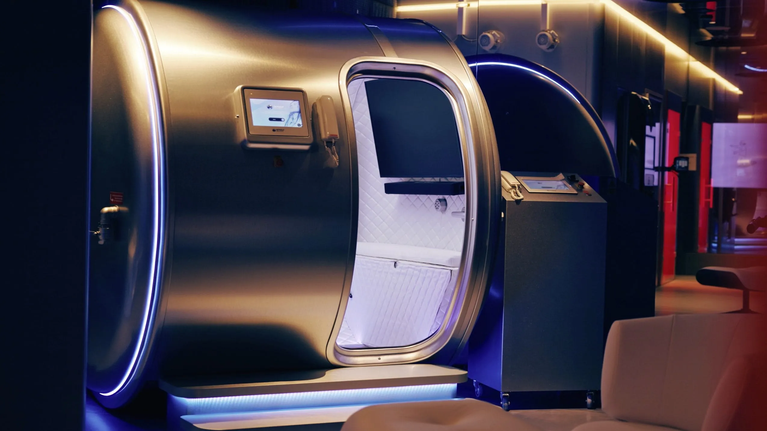 Futuristische Sauerstoffkammer mit beleuchtetem Eingangsbereich und interaktivem Bedienpanel im Huus Quell