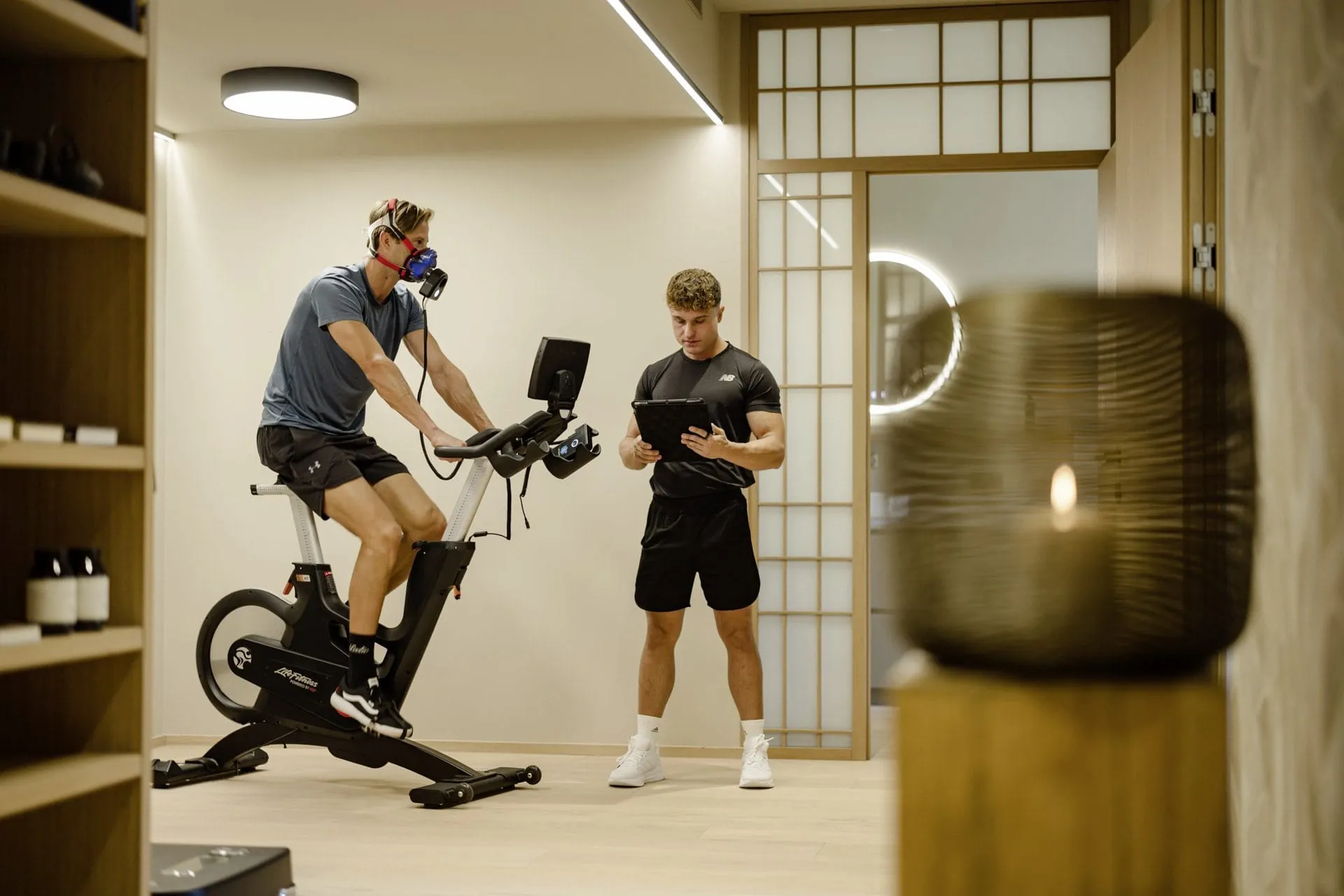 Mann auf einem Ergometer w&auml;hrend einer Leistungsdiagnostik, betreut von einem Trainer im Longevity Lab des Posthotel Achenkirch