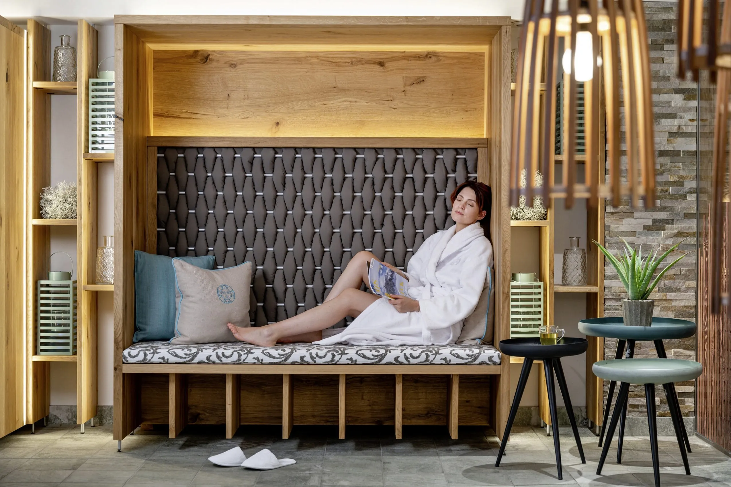 Frau im Entspannungsbereich des Sonnenalp Resort mit gem&uuml;tlicher Sitznische, Dekoration und moderner Beleuchtung