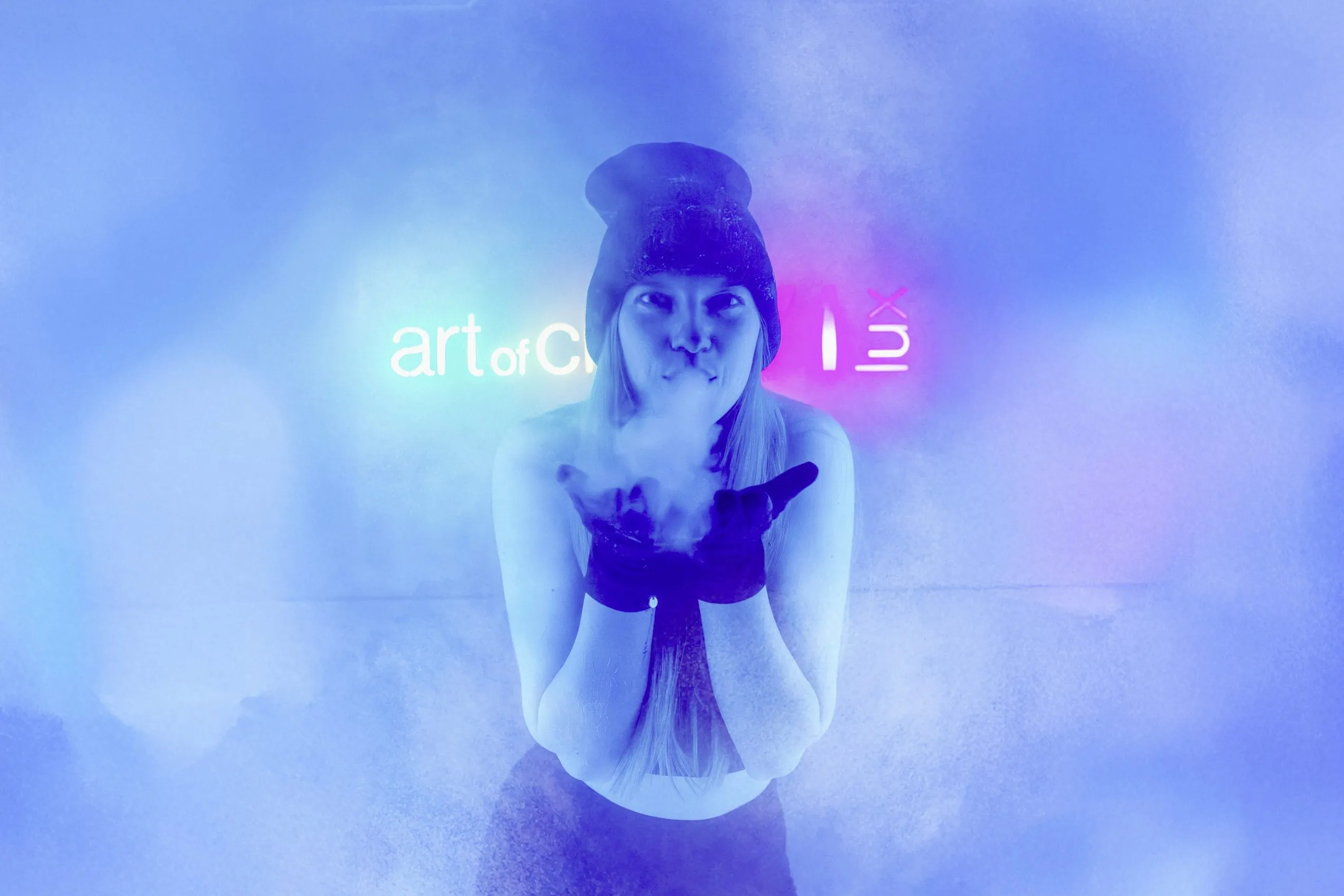 Frau in der Kältekammer des Wellness- und Naturresort Reischlhof mit Handschuhen und Mütze, von blauem Licht und Nebel umgeben