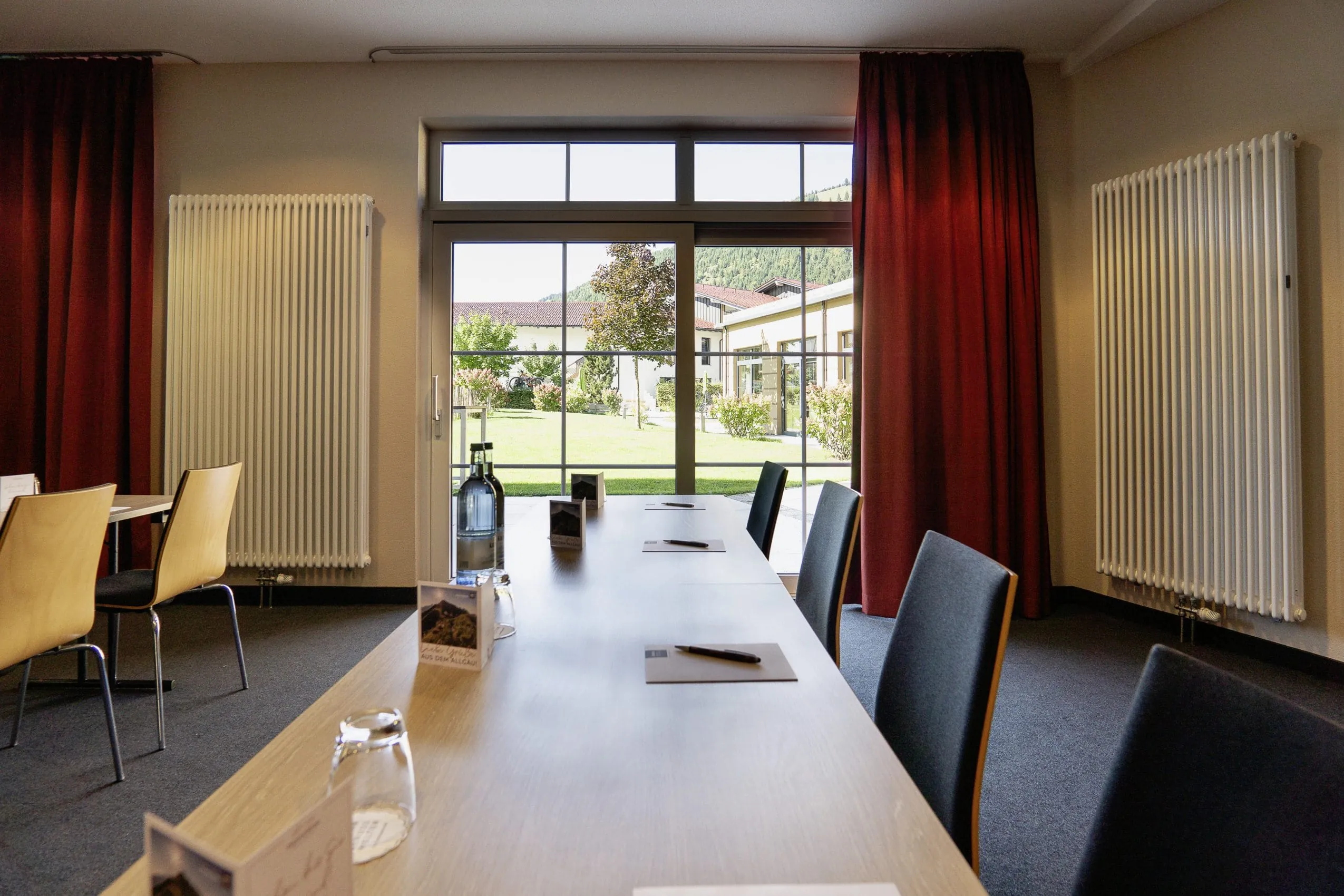 Moderner Tagungsraum im Panoramahotel Oberjoch mit Blick durch gro&szlig;e Fenster auf den gr&uuml;nen Au&szlig;enbereich