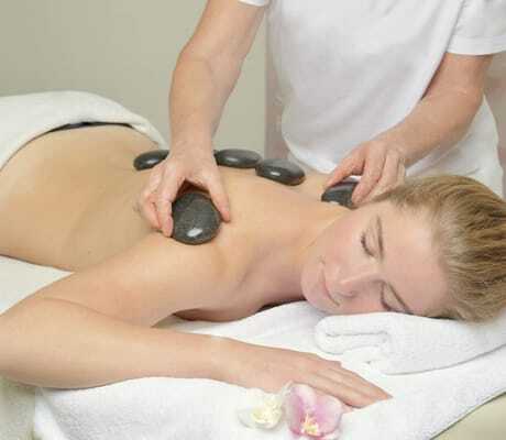 blonde Frau erhält Hot Sone-Massage im Alpenhof Oberstdorf