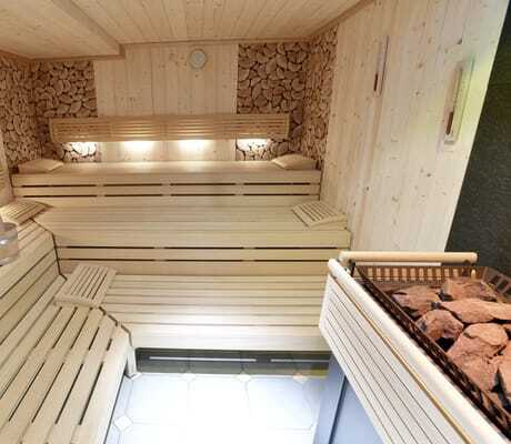 Blick in die Sauna im Alpenhof Oberstdorf mit beleuchteter Rückwand