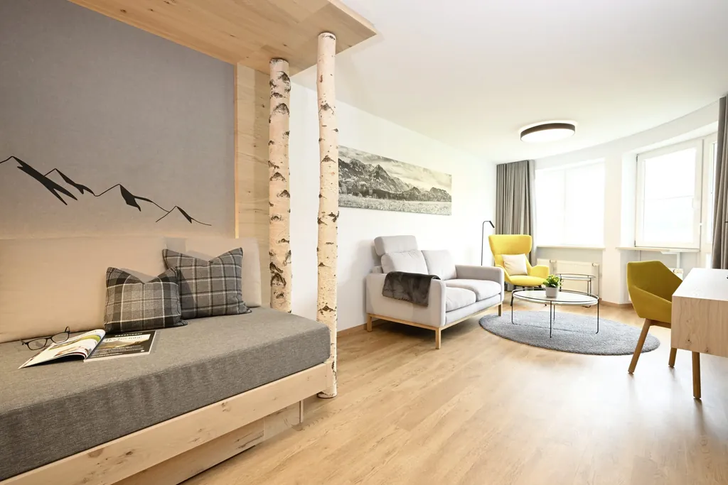 Zimmer im Alpenhof Oberstdorf mit Sofa mit Birkenstämmen und gelbem Sessel