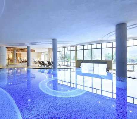 geschwungener Indoorpool im Hotel Post Lermoos mit Säulen und Schleuse zum Außenpool