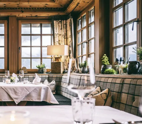 rustikales Restaurant im Hotel Post Lermoos mit karierten Polstern und Blick auf Schneelandschaft