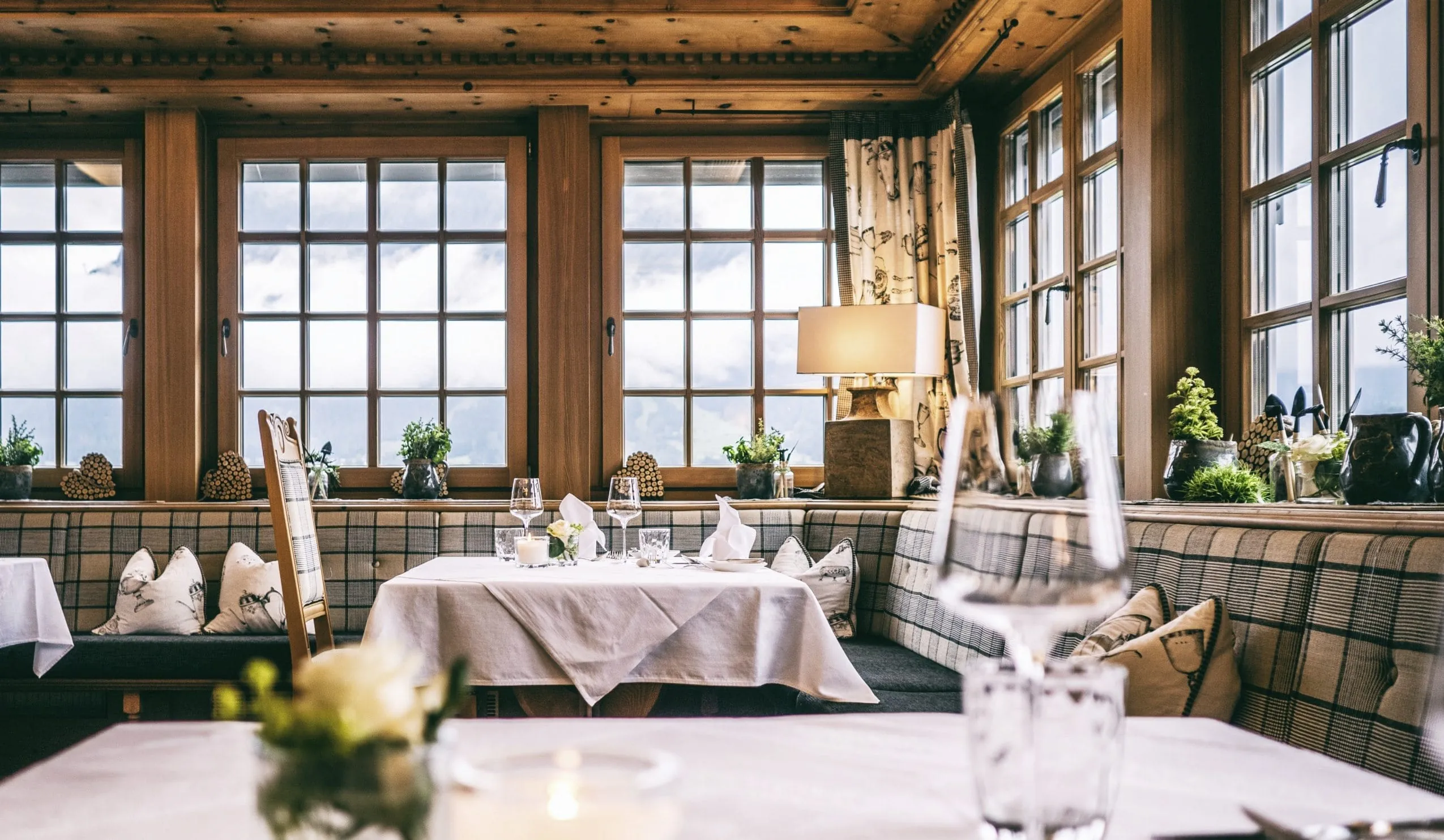 rustikales Restaurant im Alpine Luxury Hotel Post Lermoos mit karierten Polstern und Blick auf Schneelandschaft