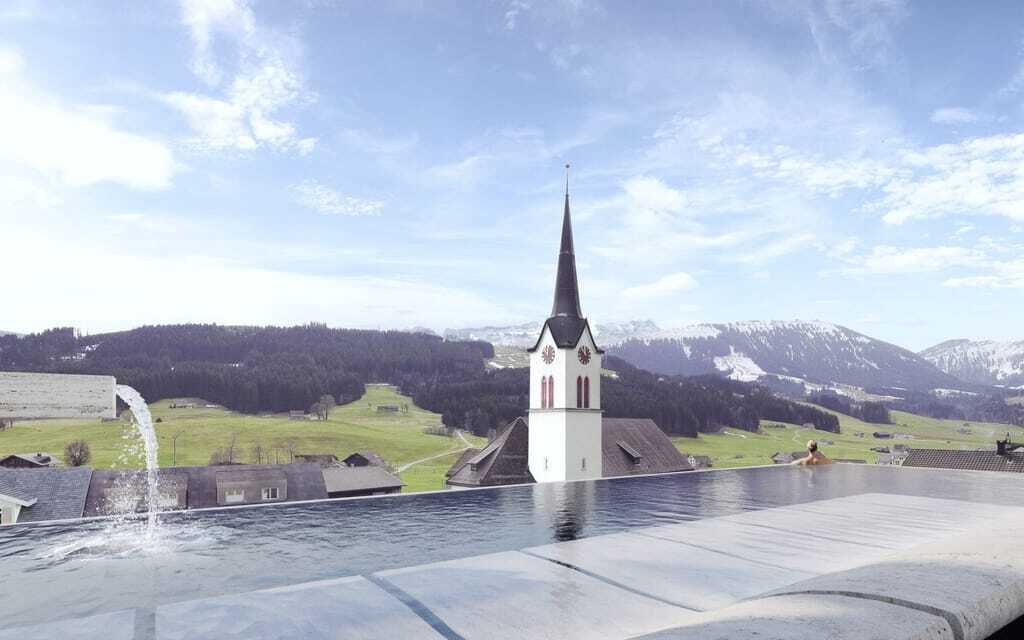 Frau steht am Beckenrand des Infinitypools auf dem Dach des Huus Quell