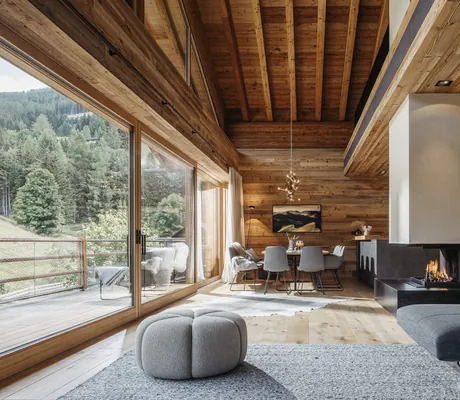 Lounge im Chalet Falk mit offenem Kamin und Blick auf den Essbereich mit hohen Holzdecken