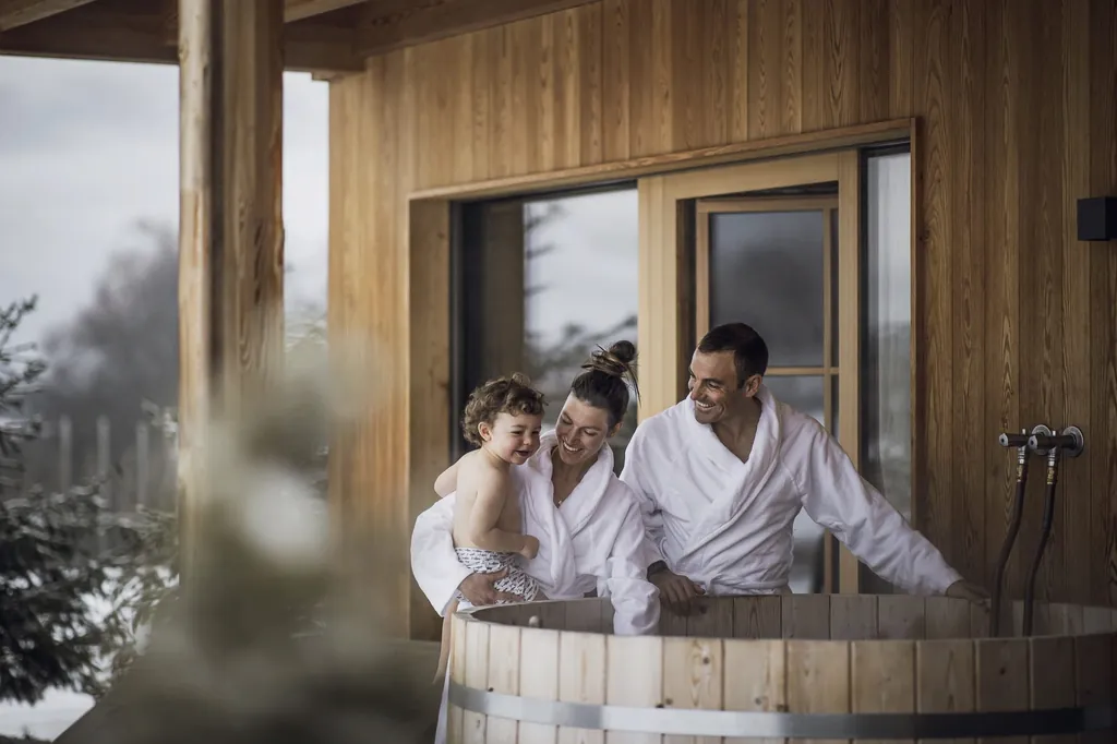 Familie mit Kleinkind in weißen Bademänteln steht am Hot Tub in Kessler's Mountain Lodge