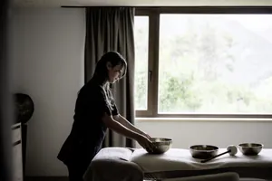 Therapeutin richtet Klangschalen auf einer Liege im Das Mühlwald her