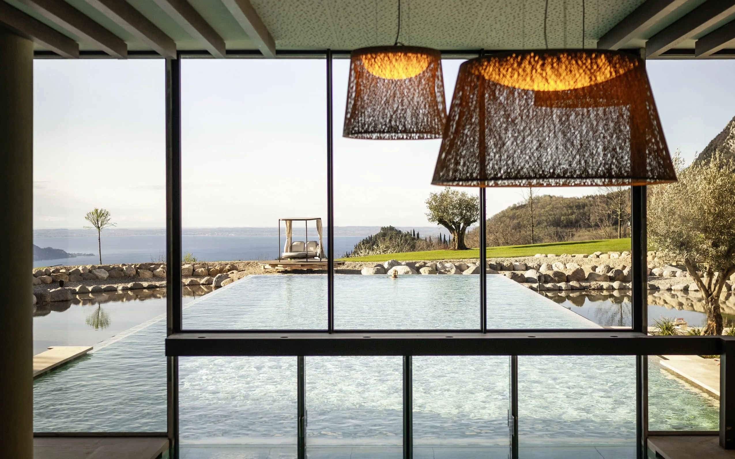 geflochtene Deckenlampen vor dem Outdoorpool des Stroblhof Lake Garda mit Blick auf den See
