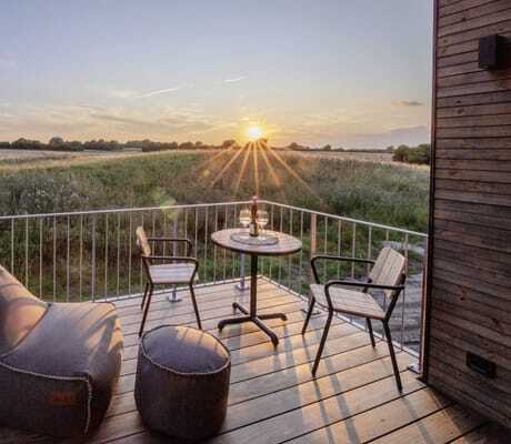 Sitzsack und Gartentisch mit zwei Stühlen auf der Terrasse des Ostsee Baumhaushotel im Abendrot