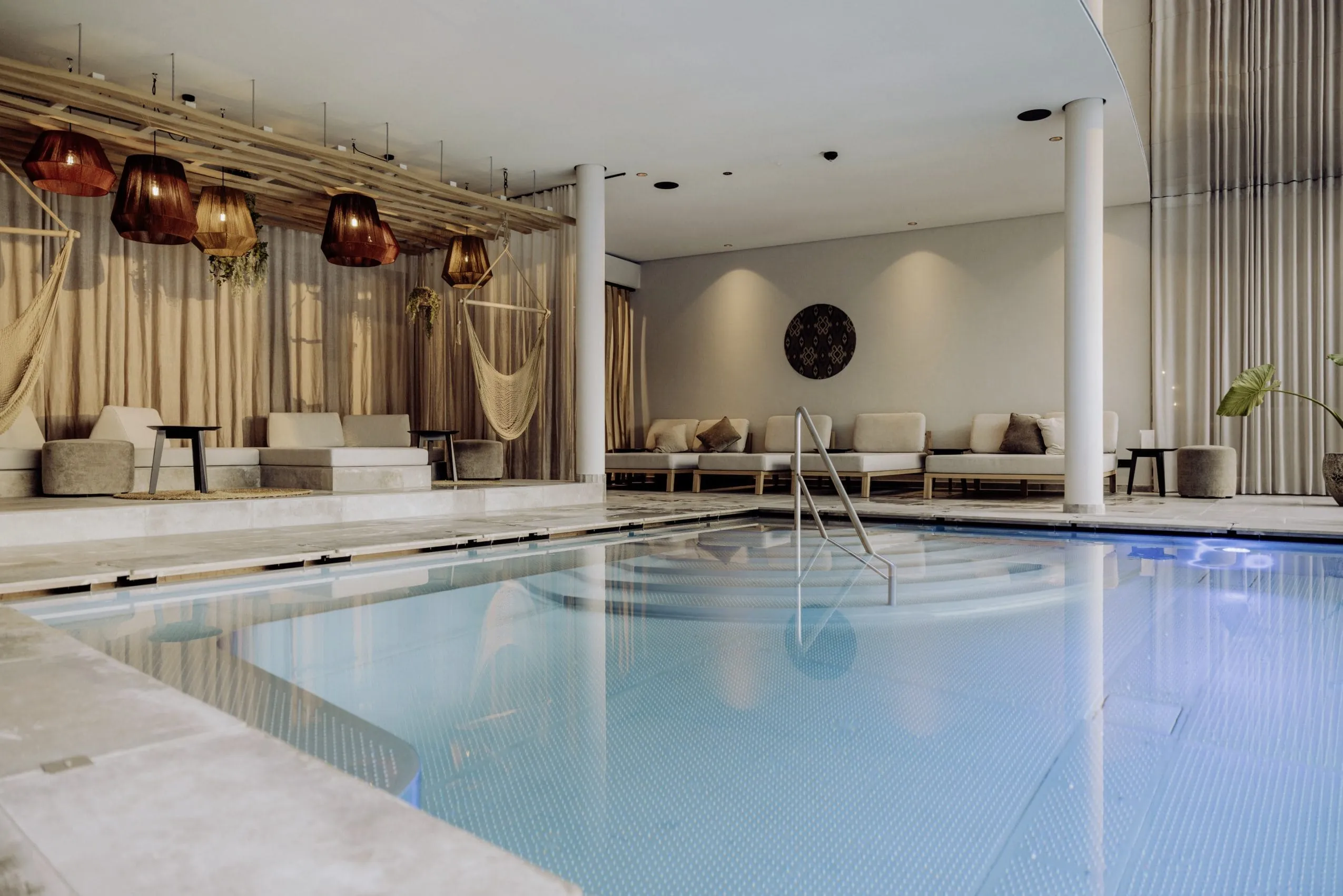Moderner Innenbereich im Naturresort PURADIES mit Pool, Sitzbereich mit Daybeds und H&auml;ngeschaukeln