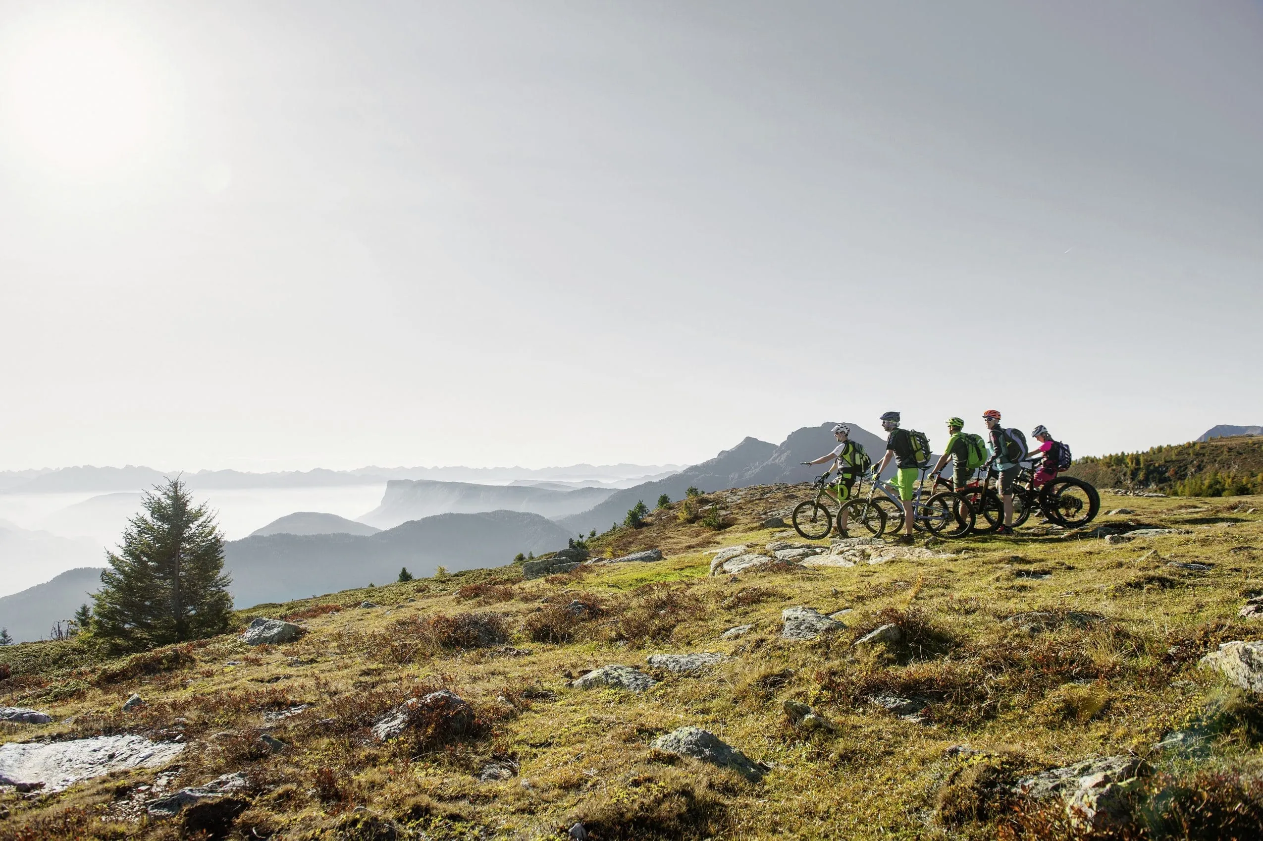 Gruppe von Bikern steht auf einer Anh&ouml;he und schaut ins Meraner Land im Nebel in der N&auml;he des Preidlhof Luxury DolceVita Resort