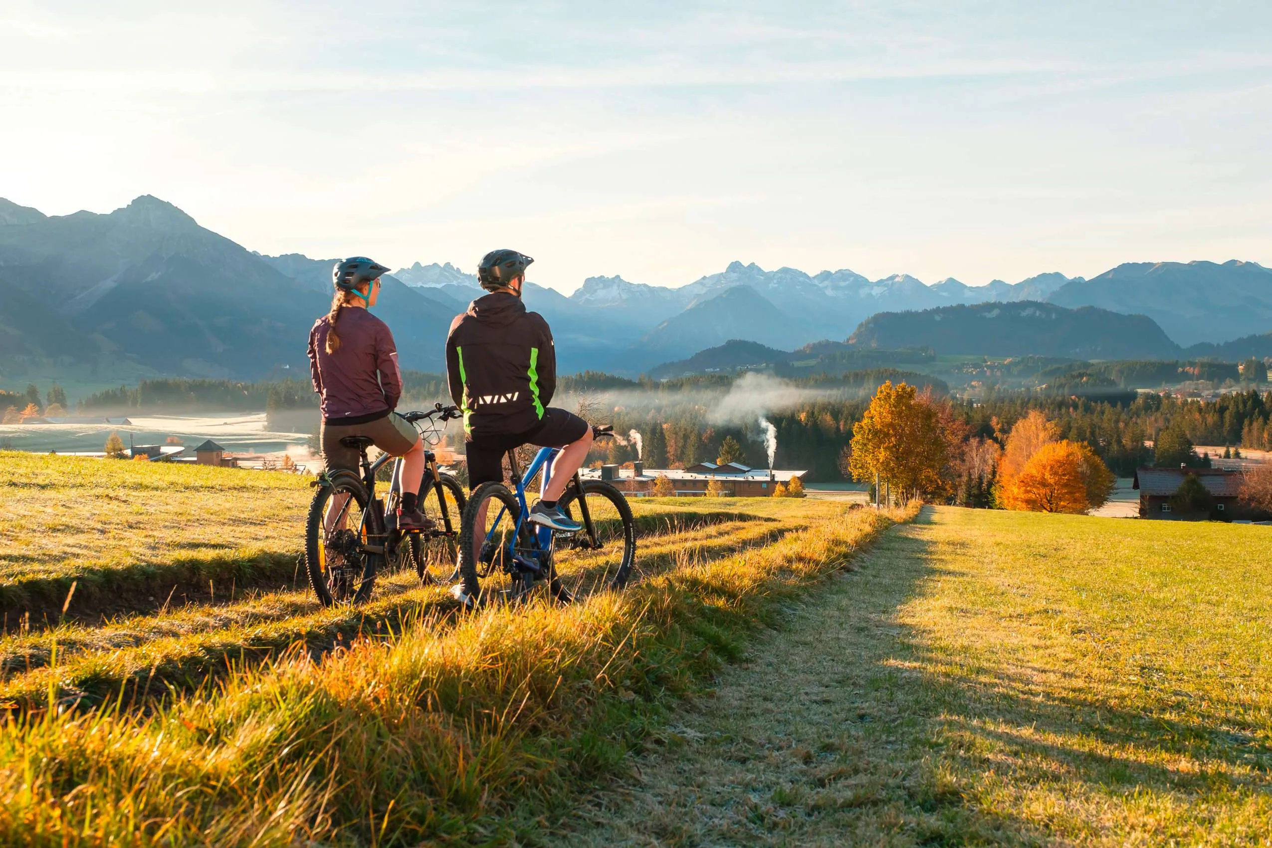 Zwei Fahrradfahrer pausieren auf einer Wiese beim Sonnenalp Resort