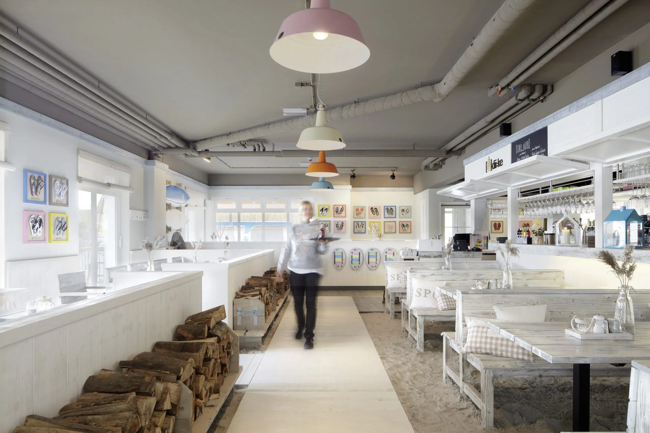 Restaurant dii:ke im maritimen Stil mit Tischen, Bar und einer Servicekraft