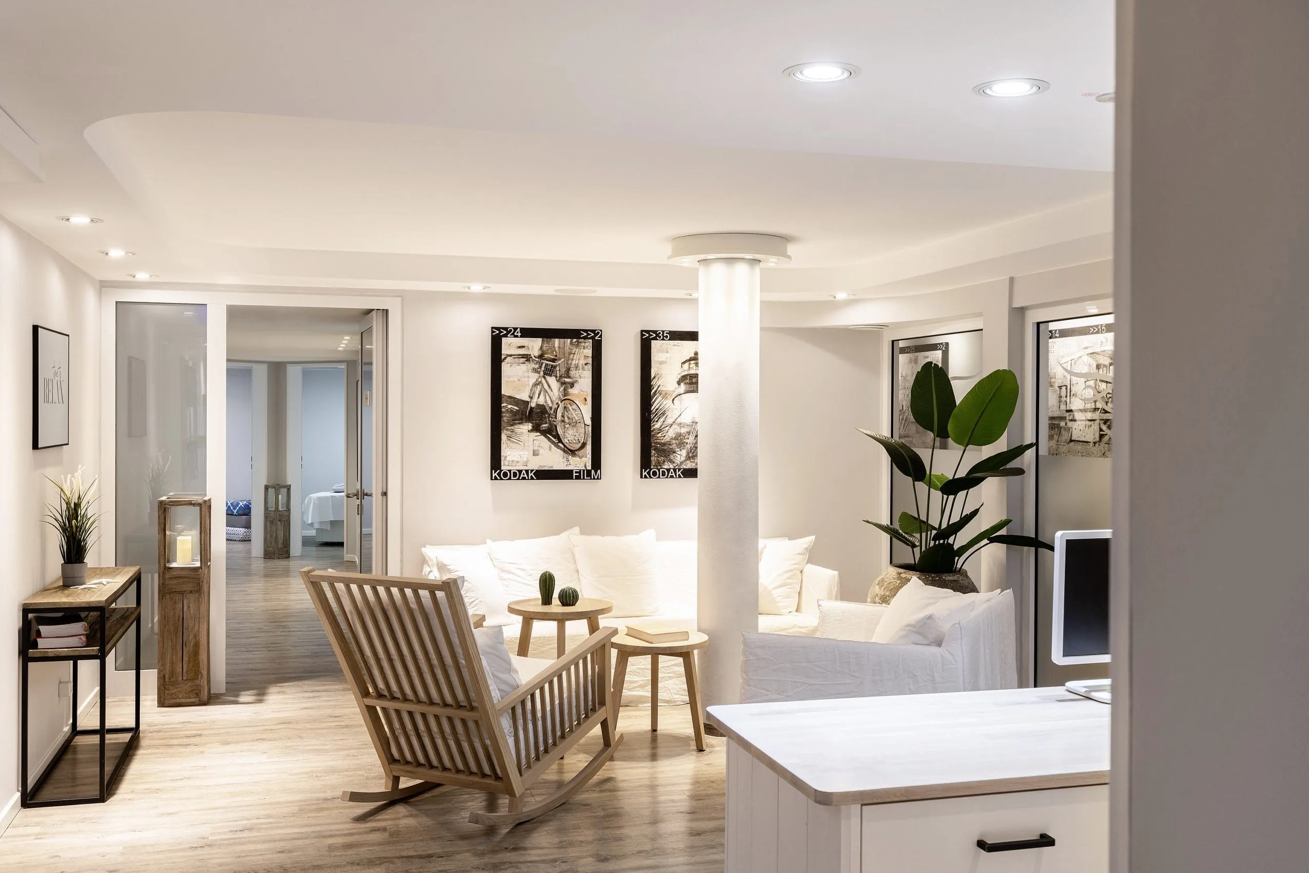 Blick in den Spabereich des Beach Motel St. Peter-Ording mit Holz-Schaukelstuhl, gem&uuml;tlichem, wei&szlig;en Sofa und schwarz-wei&szlig; Bildern an der Wand