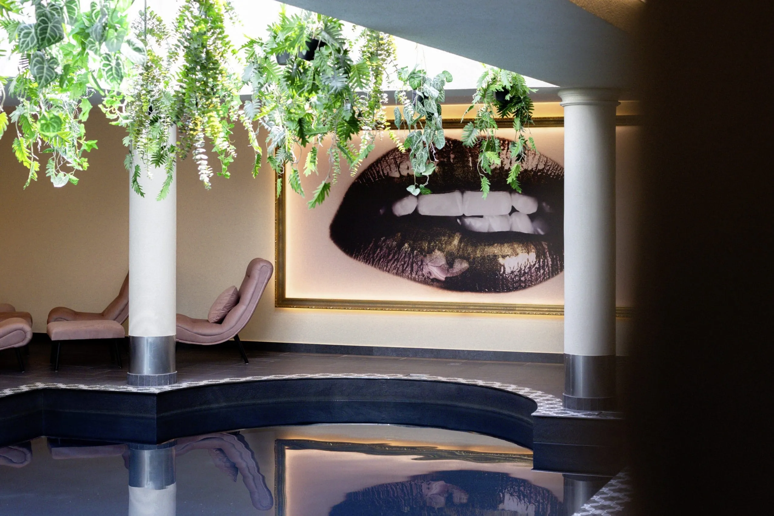 Indoorpool im LechLife Travelhouse mit von der Decke h&auml;ngenden Gr&uuml;npflanzen und modernen Fotografien an den W&auml;nden