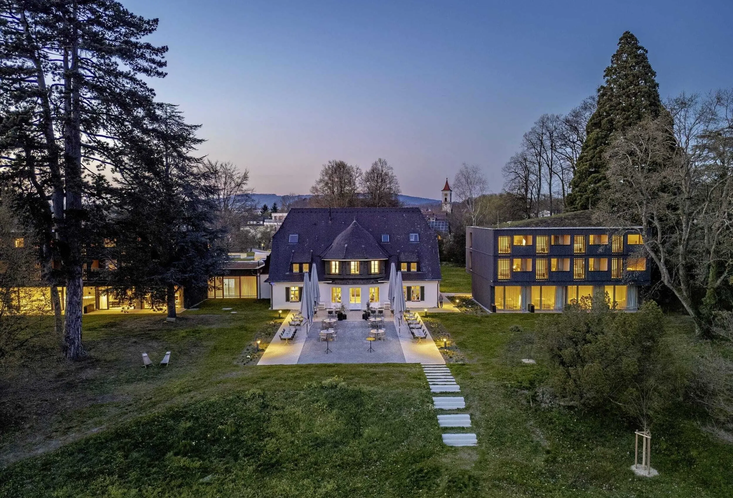 beleuchtetes Restaurant und Nebengeb&auml;ude des Seegut Zeppelin mit Terrasse