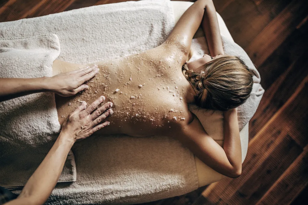 Hände massieren den Rücken einer Frau während einer Spa-Behandlung im Hotel Quelle Nature Spa Resort