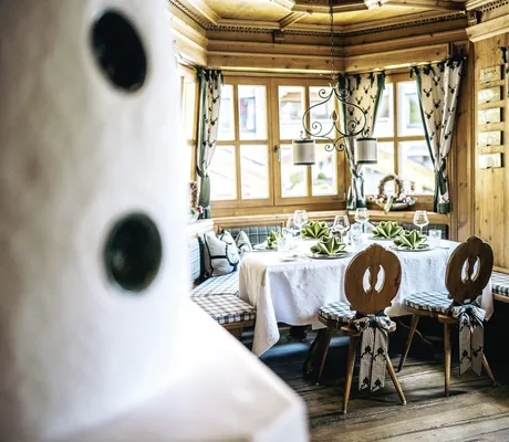 Gemütliche Kaminstube der Wellnessresidenz Alpenrose mit rustikalen Holzmöbeln und gedecktem Tisch