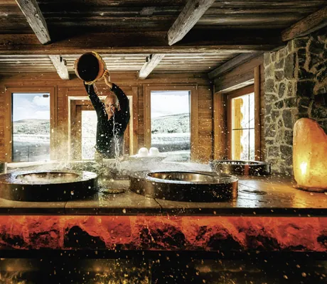 Erlebnissauna in der Wellnessresidenz Alpenrose mit Salzlampen und einer Person beim Aufguss