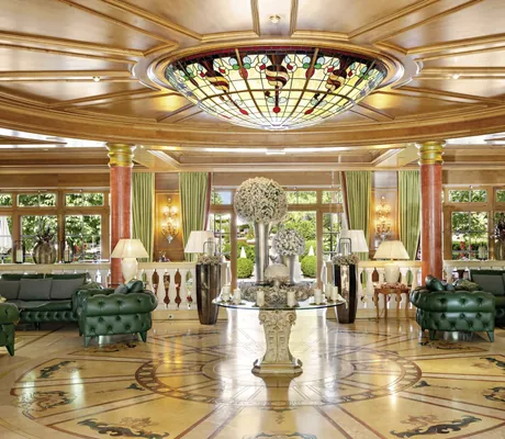 Elegante Hotellobby der Wellnessresidenz Alpenrose mit Glaskuppel, grünen Sofas und dekorativen Blumenarrangements