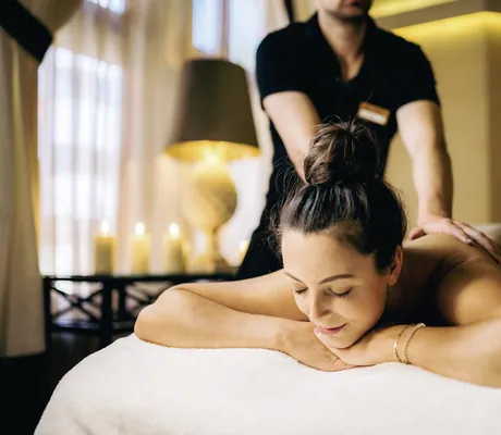 Frau bei einer entspannenden Rückenmassage in einem stimmungsvoll beleuchteten Raum in der Wellnessresidenz Alpenrose