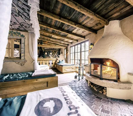 Gemütlicher Ruheraum der Wellnessresidenz Alpenrose mit Kamin, Holzliegen und rustikalem Design