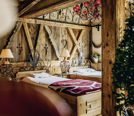 Traditioneller Ruheraum der Wellnessresidenz Alpenrose mit rustikalen Betten und dekorativen Lampen