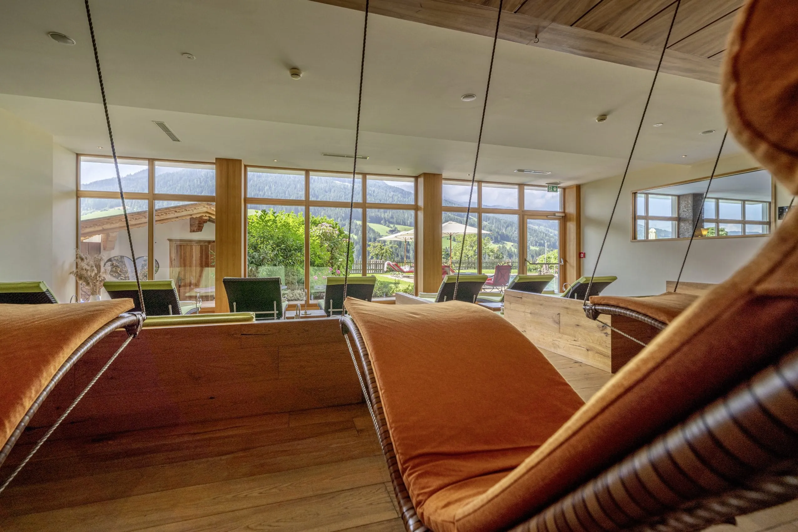 orange H&auml;ngeliege im Ruheraum des Alpbacherhof mit Blick in den Garten