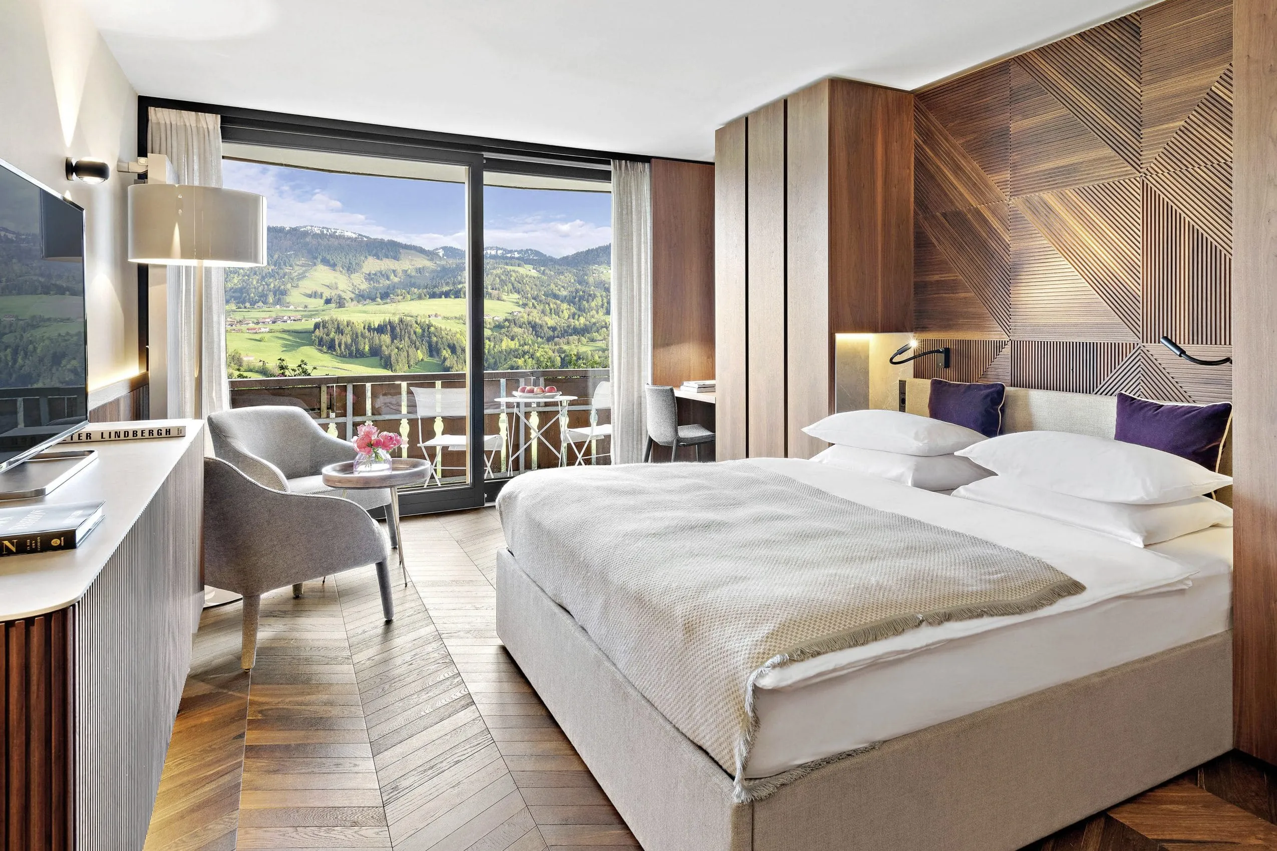 Doppelzimmer im Hotel Allg&auml;u Sonne mit Holzvert&auml;felung am Bettkopf und Blick &uuml;ber den Balkon in die Berge