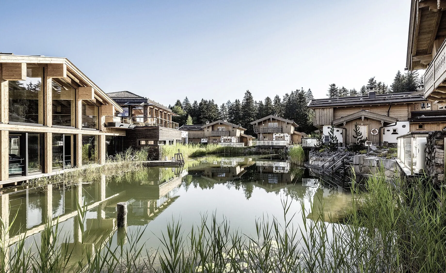 Naturbadeteich im INNs Holz Resort umringt von Chalets und Wellnessbereich