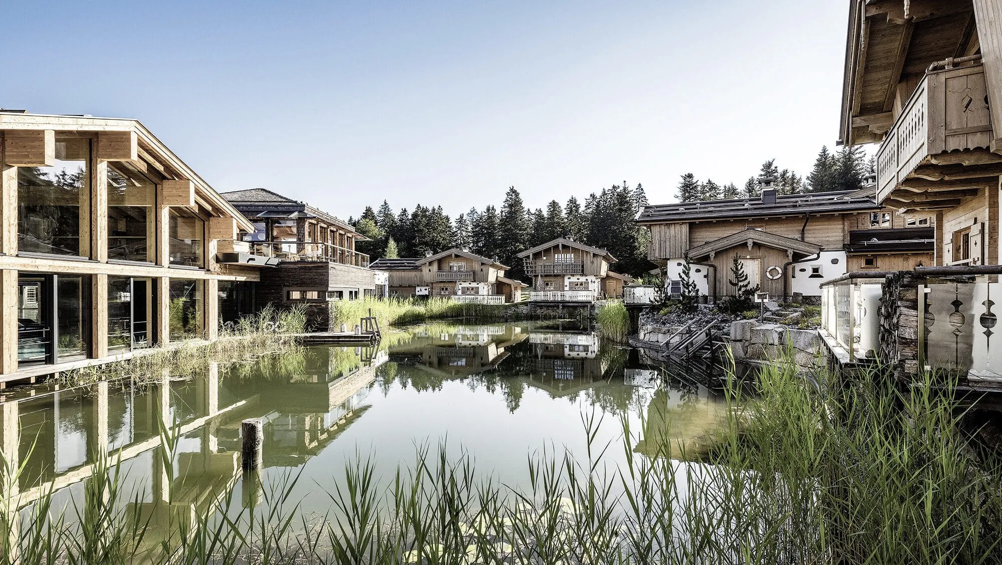 Naturbadeteich im INNs Holz Resort umringt von Chalets und Wellnessbereich