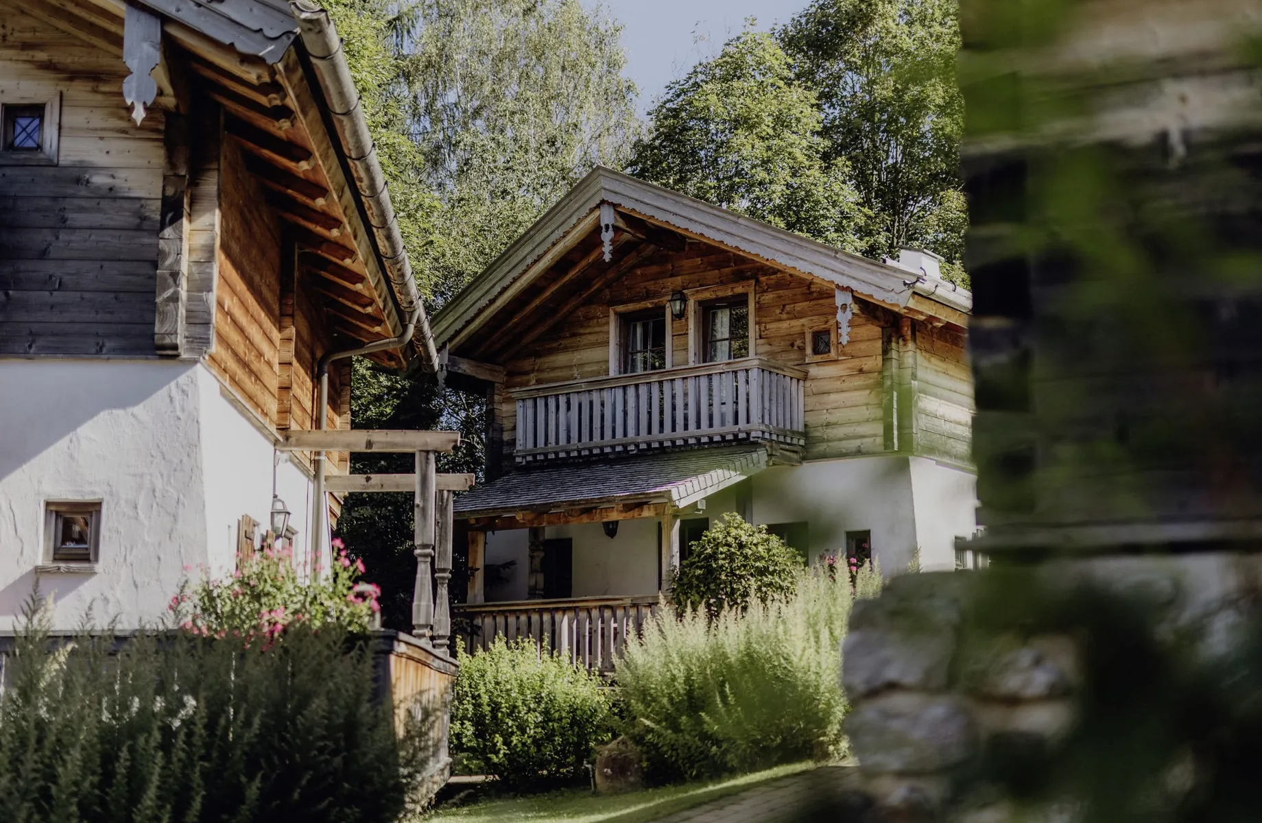 Traditionelle Chalets im Naturresort PURADIES mit Holzfassaden und üppiger Gartenlandschaft