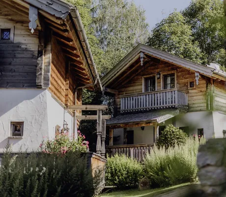 Traditionelle Chalets im Naturresort PURADIES mit Holzfassaden und üppiger Gartenlandschaft