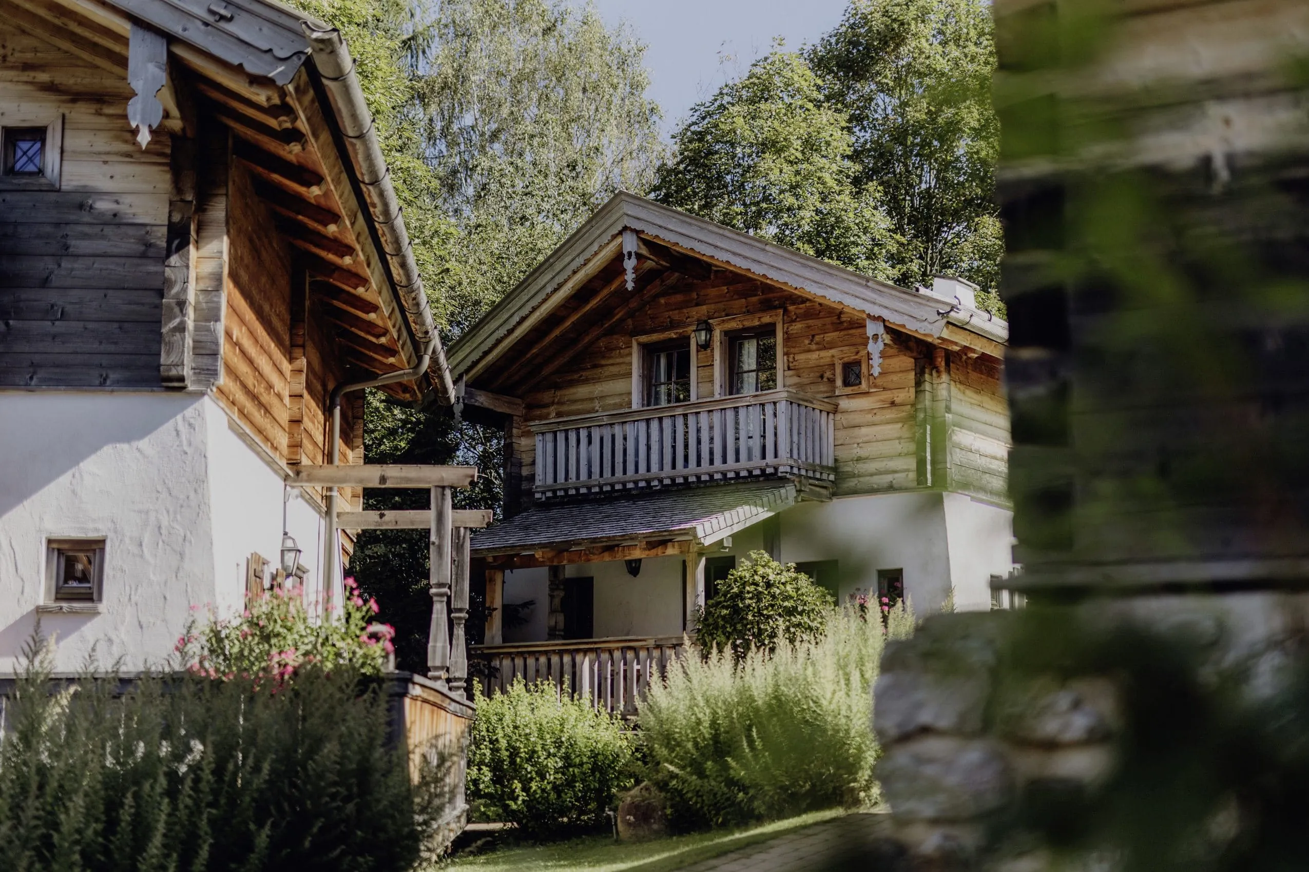 Traditionelle Chalets im Naturresort PURADIES mit Holzfassaden und üppiger Gartenlandschaft
