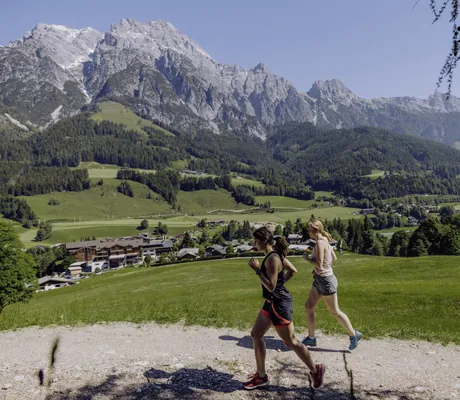 Zwei Frauen joggen in der Nähe des Naturresort PURADIES mit Bergpanorama im Hintergrund